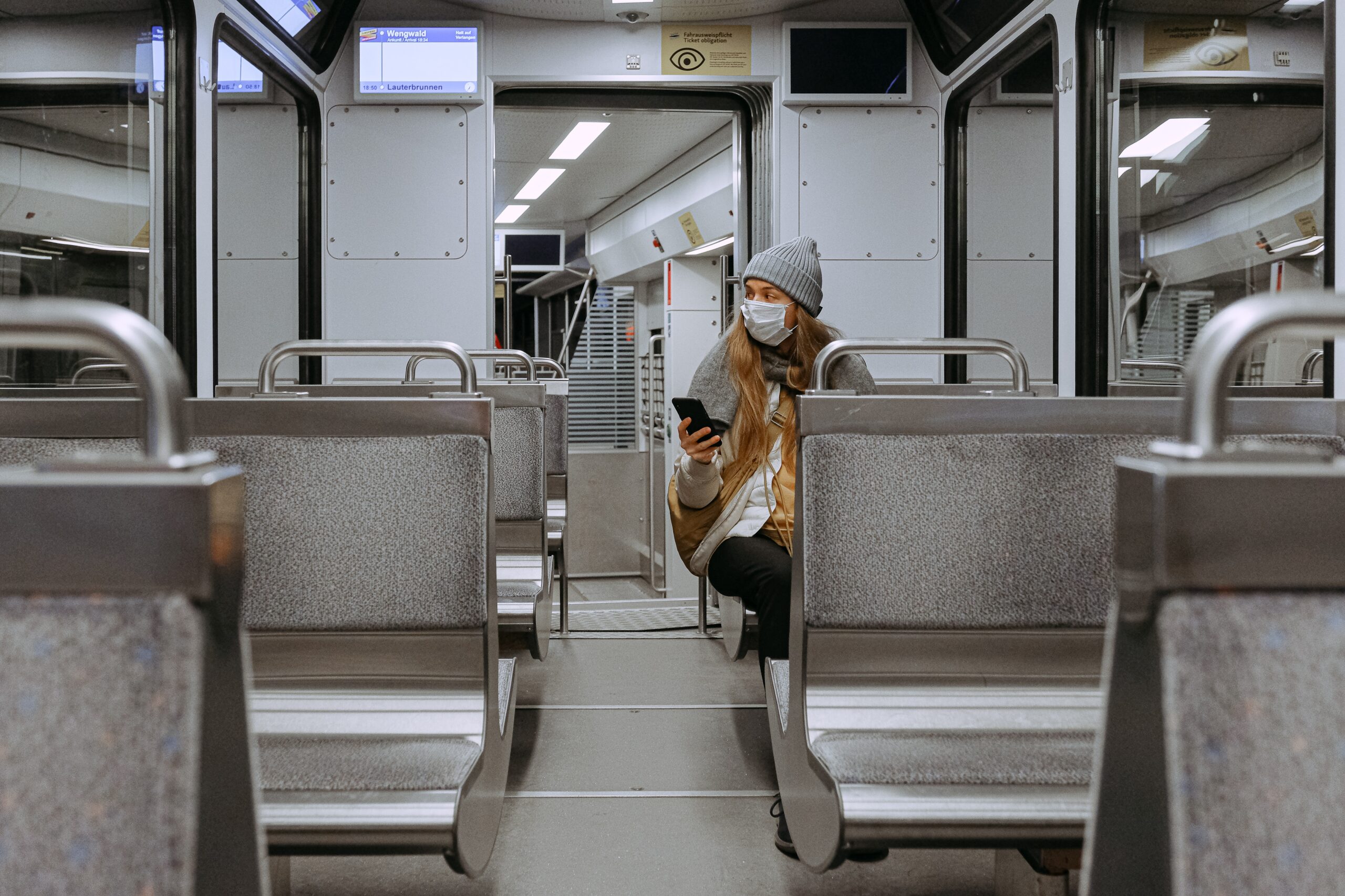 mulher com máscara e celular em trem